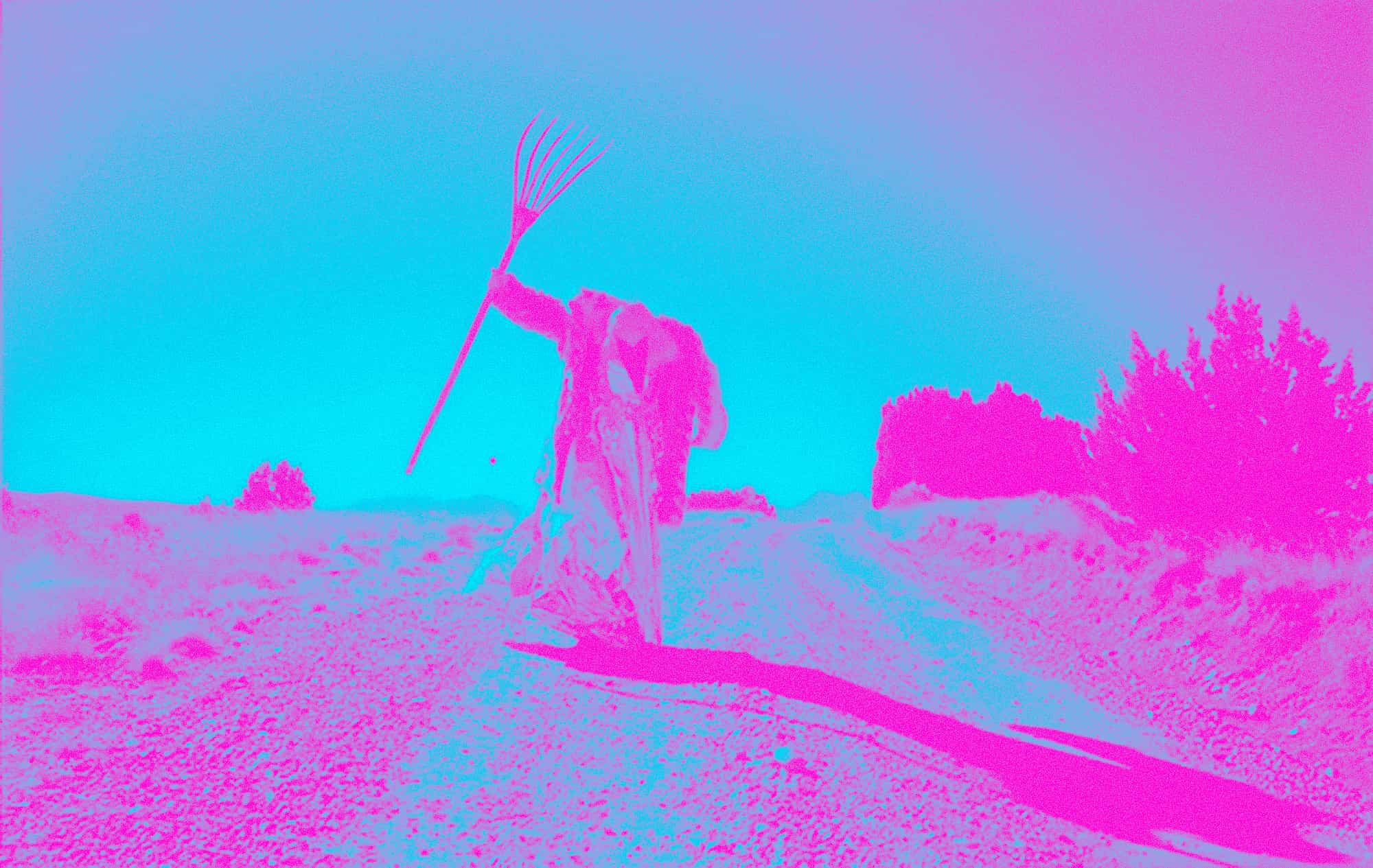 Devil-like figure with rake dances in a country-side path